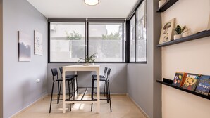A modern room with a large window, a table with chairs, and shelves with books and decorative items. - Serenity by the Sea – Poleg Villa by Sea N' Rent (Netanya)