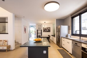 A modern kitchen with a central island, stainless steel appliances, and a large window. - Serenity by the Sea – Poleg Villa by Sea N' Rent (Netanya)