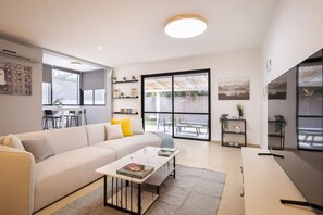 A modern living room with a sofa, coffee table, and shelves with plants. - Serenity by the Sea – Poleg Villa by Sea N' Rent (Netanya)