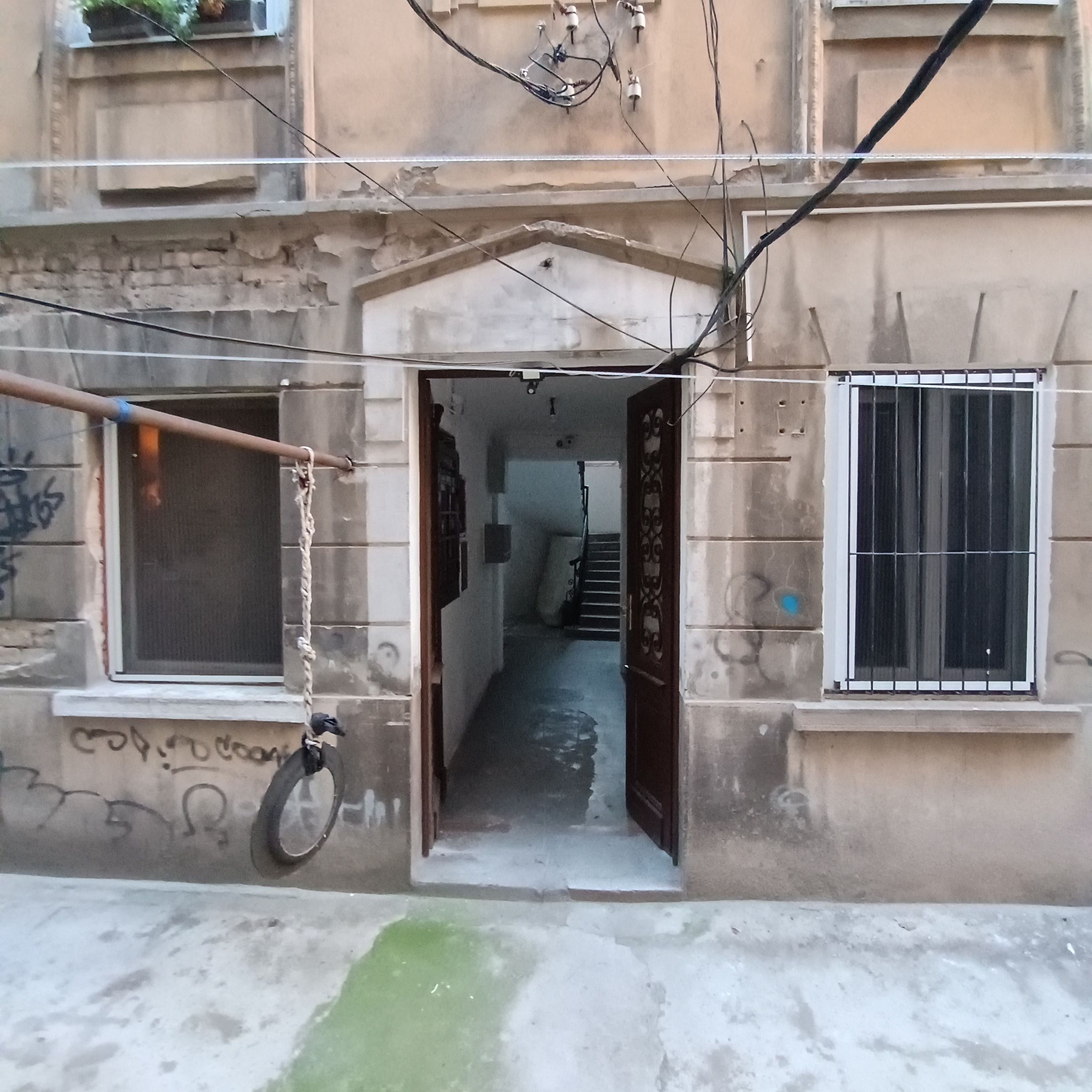 A building with a central doorway, a window on the left, and a barred window on the right.