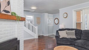 A living room with a fireplace, a grey couch, and a wooden coffee table. - Charming Downtown Bungalow with Yard & Gas Grill (Oshkosh)