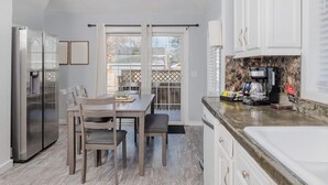 A modern kitchen with a dining area, stainless steel appliances, and a stone backsplash. - Charming Downtown Bungalow with Yard & Gas Grill (Oshkosh)