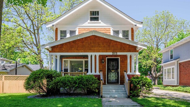 A two-story house with a front porch, a number '212' on the door, and a brick facade. - Charming Downtown Bungalow with Yard & Gas Grill (Oshkosh)