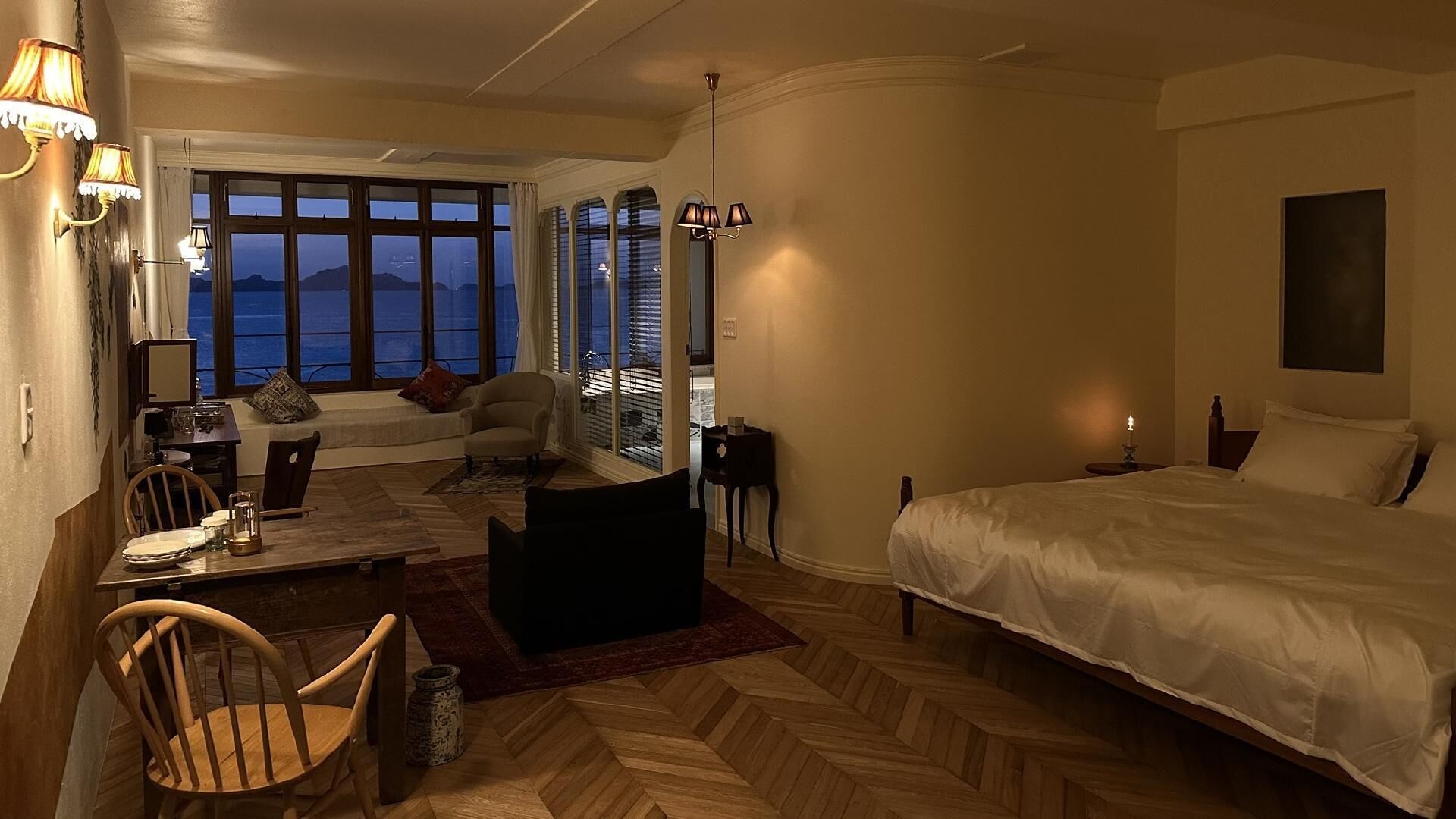 Een hotelkamer met een bed, een bureau met stoel, een bank en uitzicht op de bergen.