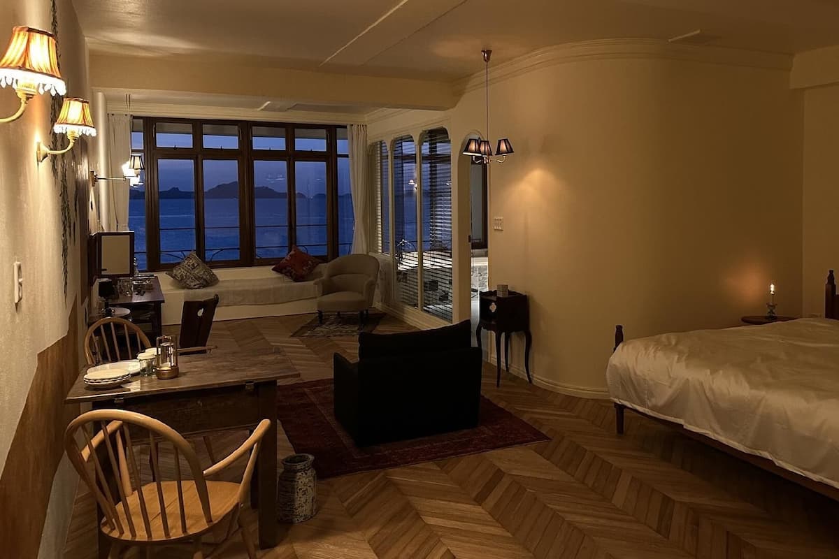 Ein Hotelzimmer mit einem Bett, einem Schreibtisch mit Stuhl, einer Sitzecke und Blick auf die Berge.