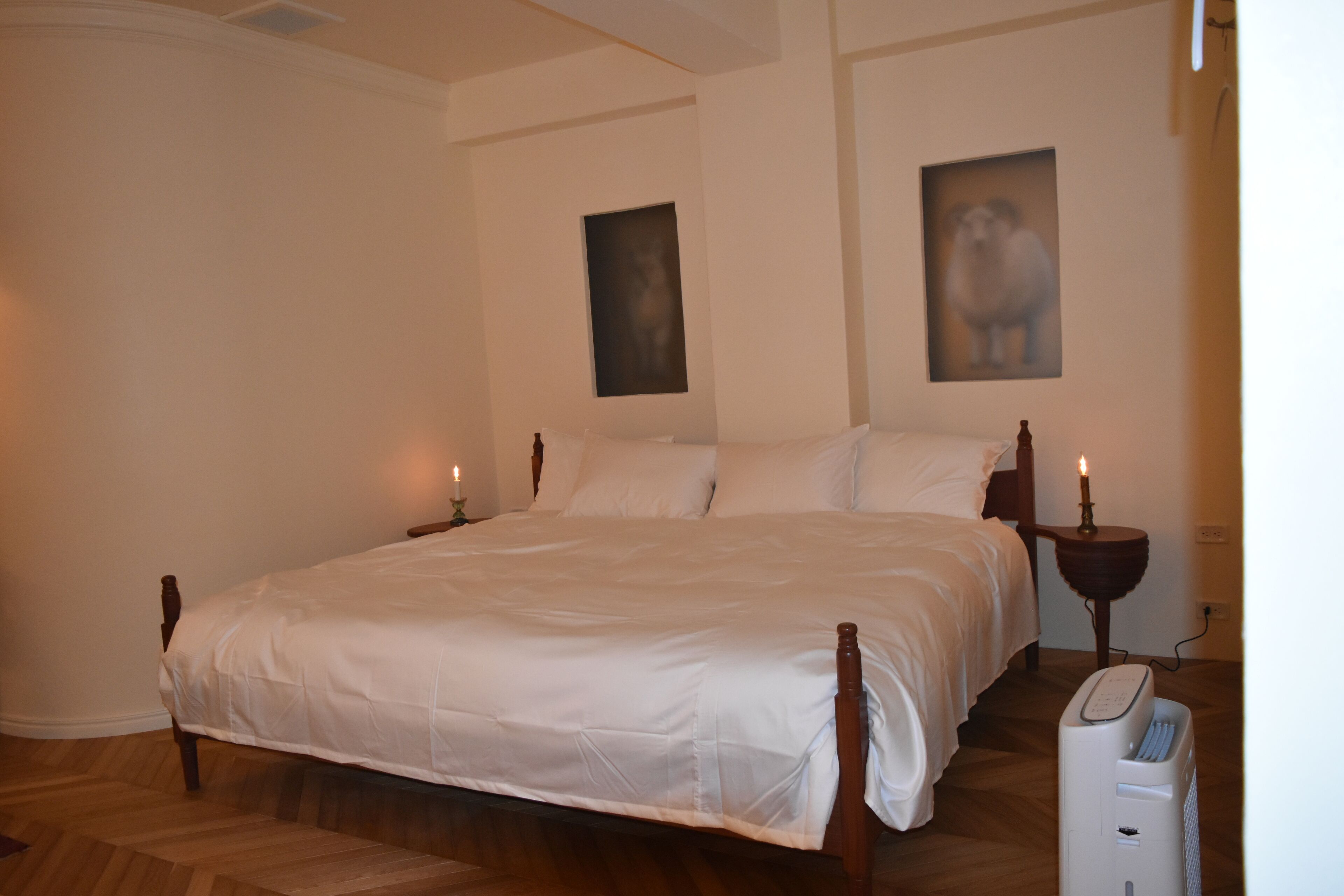 Quarto com cama grande, duas mesinhas de cabeceira e aquecedor fixado na parede.