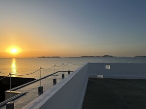 Vista del atardecer desde un balcón con barandilla y cielo despejado.