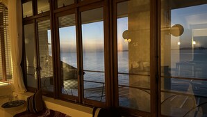 Una habitación con un ventanal grande con vistas a un cuerpo de agua, una mesita y una silla.