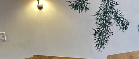 Una mesa de madera con sillas, una lámpara fijada en la pared y una rama decorativa.