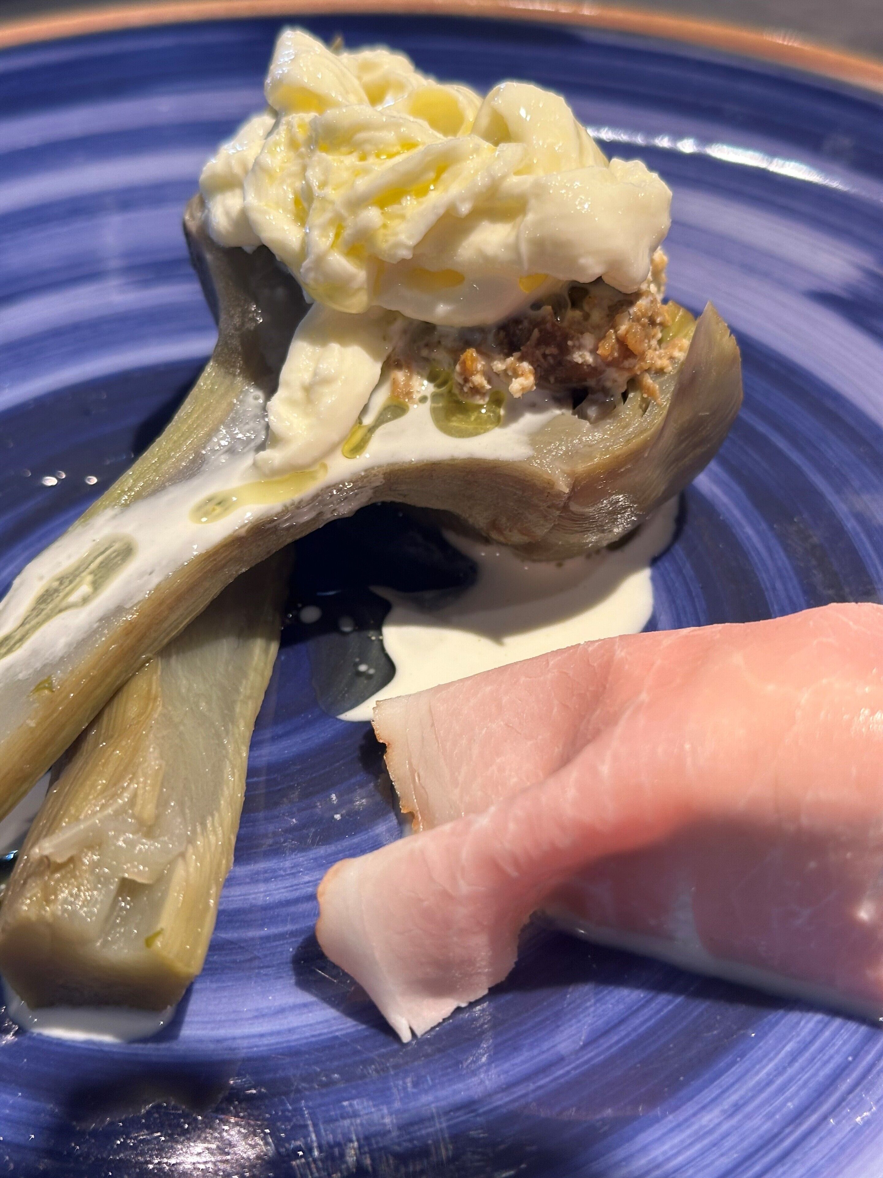 Un plato con una cobertura cremosa y un trozo de carne.
