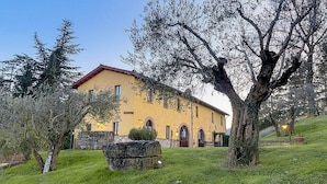 A yellow building with a stone wall, surrounded by trees and grass. - Casa Gioele D: A welcoming apartment situated in a quiet location, a few minutes from the town center, with Free WI-FI. (Umbertide)