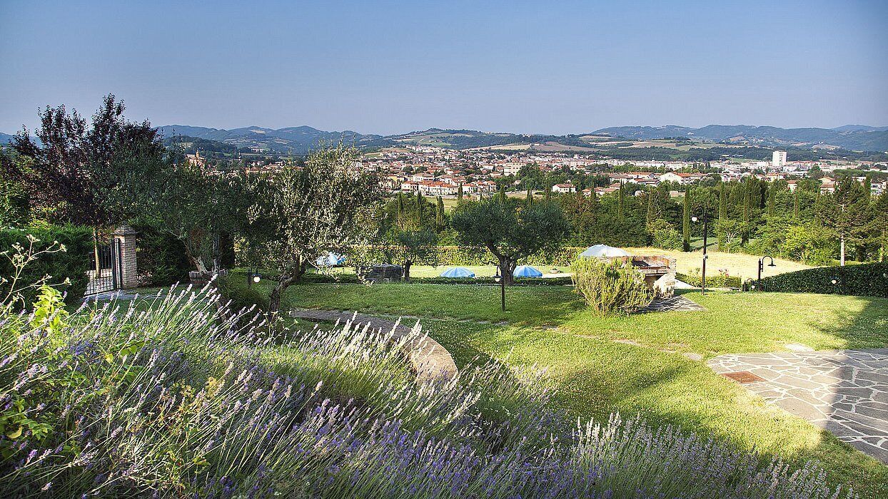 A garden with lavender, a stone pathway, and a view of a town in the distance.