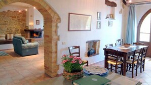 A cozy living room with a fireplace, a dining area with wooden furniture, and a stone wall archway. - Casa Gioele D: A welcoming apartment situated in a quiet location, a few minutes from the town center, with Free WI-FI. (Umbertide)