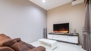 A modern living room with a brown sofa, a flat-screen TV, a white coffee table, and a fireplace. - Luxury PrivatePoolVilla Lumiere Dewi Sri (Legian)