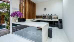 A modern kitchen with a large island, white cabinetry, and a built-in oven. - Luxury PrivatePoolVilla Lumiere Dewi Sri (Legian)