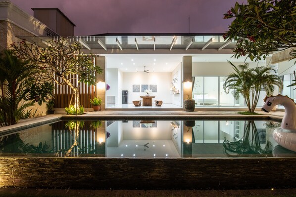 A modern pool with a glass bottom, surrounded by potted plants and a swan float. - Luxury PrivatePoolVilla Lumiere Dewi Sri (Legian)