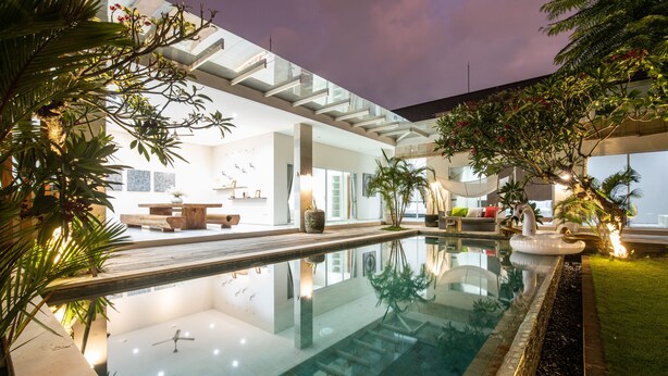 A modern indoor pool area with a glass ceiling, surrounded by lush greenery and a well-lit interior. - Luxury PrivatePoolVilla Lumiere Dewi Sri (Legian)