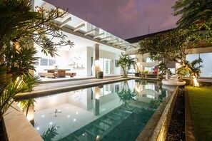 A modern indoor pool area with a glass ceiling, surrounded by lush greenery and a well-lit interior. - Luxury PrivatePoolVilla Lumiere Dewi Sri (Legian)