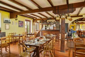 A restaurant with wooden tables and chairs, a bar area with bottles, and a tiled floor. - Farmhouse in Verbania with Lake Views (Verbania)