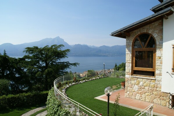 A stone building with a stone facade and a large arched window, surrounded by a well-maintained garden and a metal railing. - Charming villa in Torri del Benaco with fenced pool (Torri del Benaco)