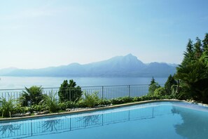 A swimming pool with a view of a mountain range and a body of water. - Charming villa in Torri del Benaco with fenced pool (Torri del Benaco)