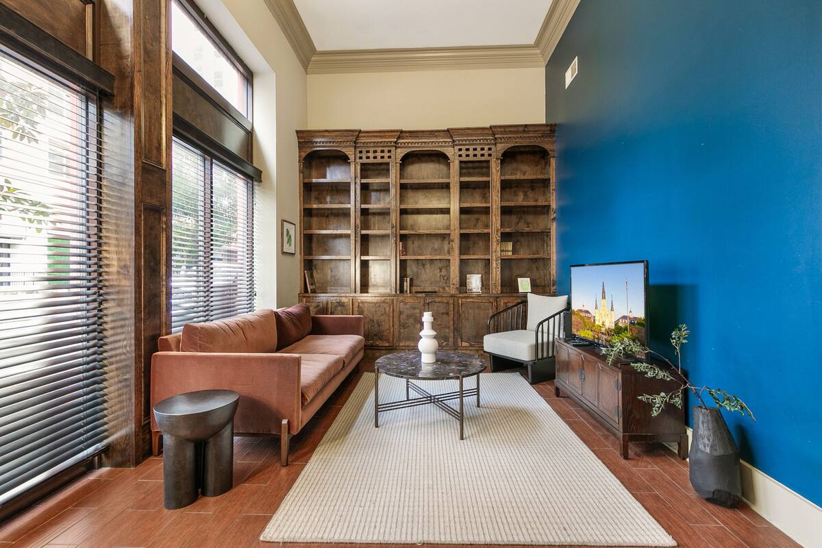 A living room with a brown sofa, a round coffee table, and a bookshelf against a blue wall.