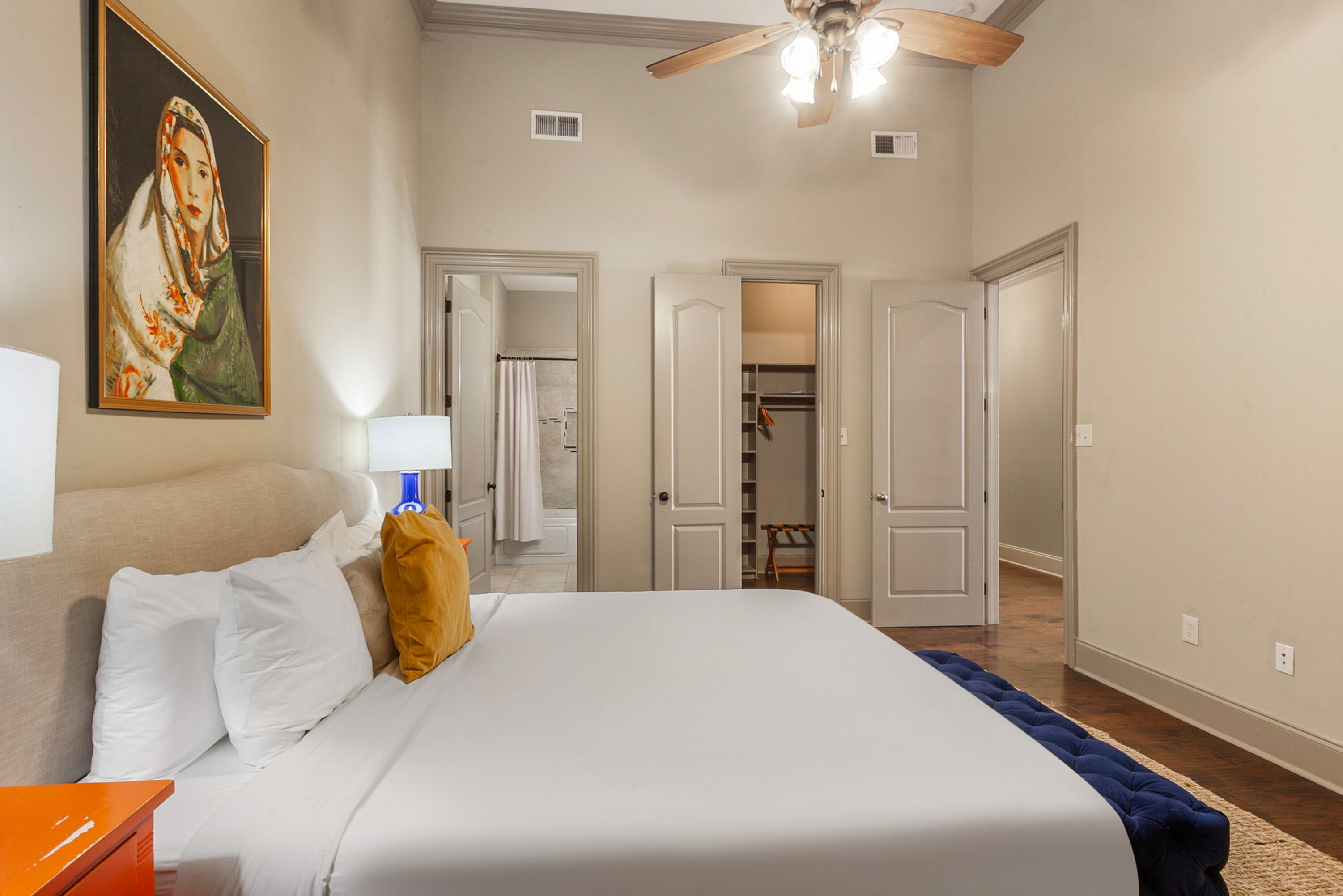 Une chambre à coucher avec un lit, un ventilateur de plafond et un tableau accroché au mur.