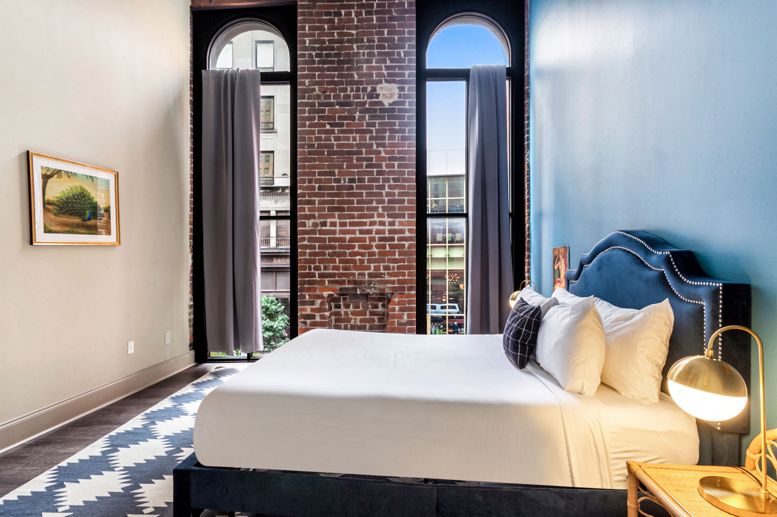 Une chambre d’hôtel avec un grand lit, une table de chevet, une lampe et une vue sur l’extérieur.
