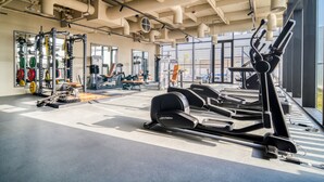 A gym with exercise equipment, large windows, and a high ceiling with exposed ductwork. - Prime Location, Pristine Studio in Business Bay (Dubai)