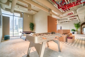 A modern indoor space with a foosball table, large windows, and a view of a cityscape.