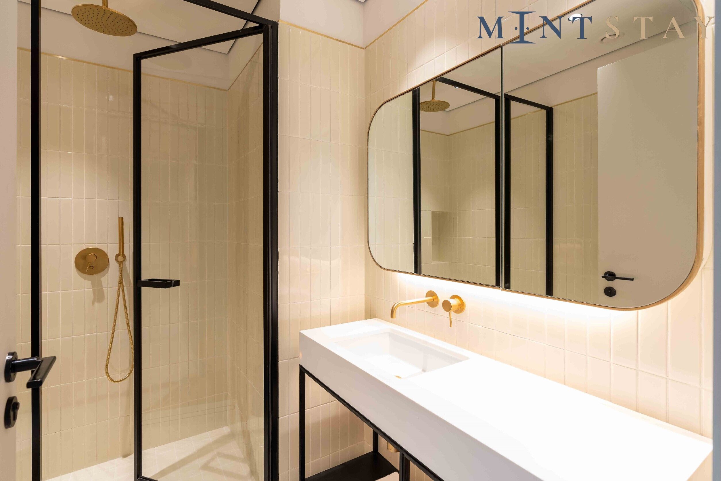 A modern bathroom with a glass-enclosed shower, a white sink, and a large mirror.