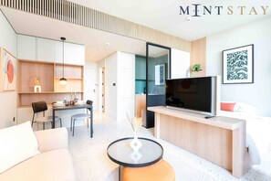 A modern hotel room with a dining area, a TV, and a sofa.
