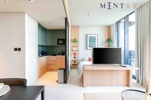 Une chambre d’hôtel moderne dotée d’un grand lit, d’une télévision, d’un bureau et offrant une vue sur la ville.