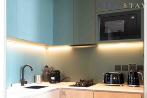 A modern kitchen with a sink, a coffee machine, a toaster, and a microwave.