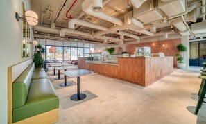 A modern interior with a reception desk, green seating area, and large windows.