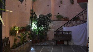 Un patio interior con escaleras, plantas en macetas y bancos.