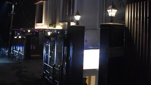 Un hotel llamado "HOTEL MARC" con señalización iluminada, una entrada con portón y una escalera que lleva a la recepción.