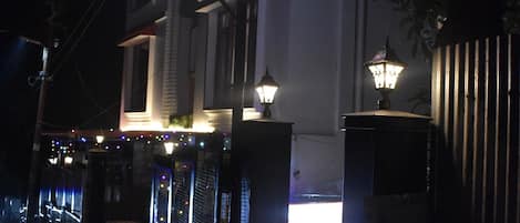 Un hotel llamado "HOTEL MARC" con señalización iluminada, una entrada con portón y una escalera que lleva a la recepción.