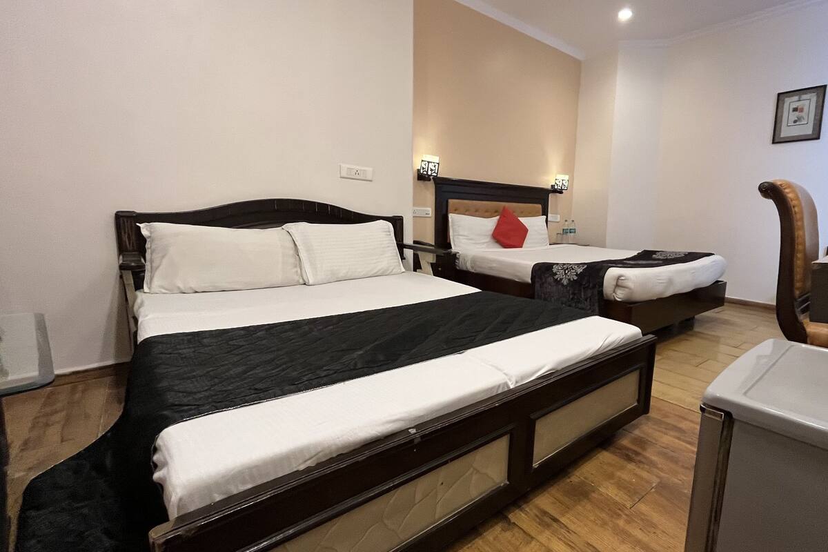 A hotel room with two single beds, a wooden headboard, a small desk, and a chair.