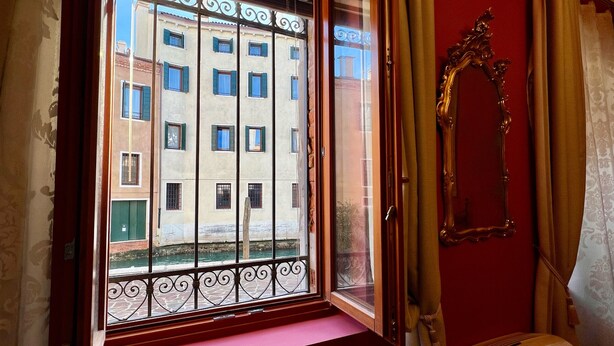 Une pièce dotée d’une grande fenêtre donnant sur un immeuble comportant de nombreuses fenêtres et des balcons.
