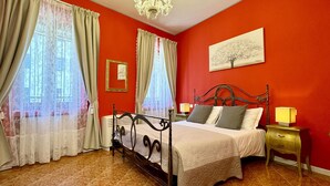 Une chambre à coucher avec un lit, une table de chevet, une lampe, un lustre et un tableau accroché au mur.