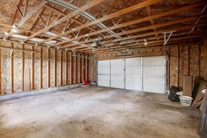 Un garaje con piso de concreto, estructura de madera y puerta corrediza blanca.