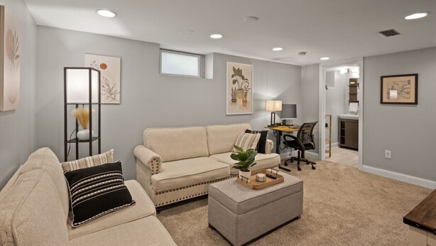 Una sala de estar con sofá, reposapiés y un escritorio con silla.