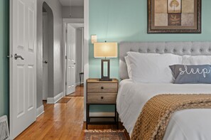 Un dormitorio con cama, lámpara de noche y un cuadro en la pared.