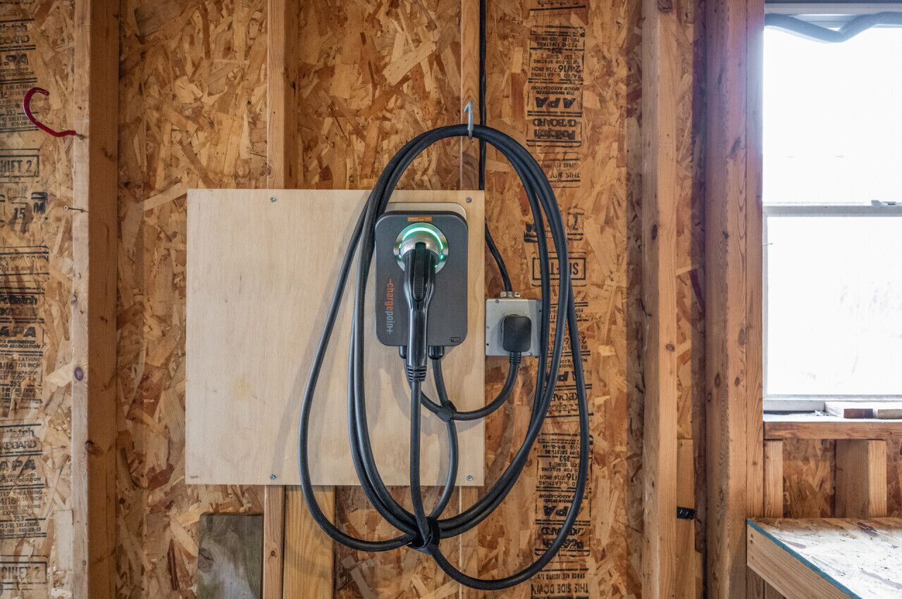 A wooden-framed room with exposed electrical wiring and a window.