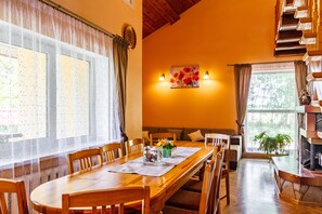 A dining area with a wooden table, chairs, and a fireplace. - Guest house Sidrabi (Druva)