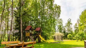Une aire de jeux avec un toboggan, des balançoires et une structure en bois.