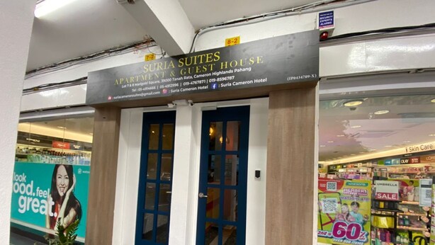 A hotel entrance with a sign for 'Suria Suites Apartment & Guest House'.