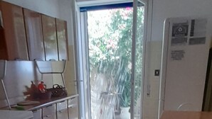 A kitchen with a dining area, a refrigerator, and a sliding glass door leading outside. - Sea view cottage (San Pietro In Bevagna)