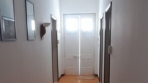 A hallway with white walls, a wooden floor, and a door at the end. - Sea view cottage (San Pietro In Bevagna)